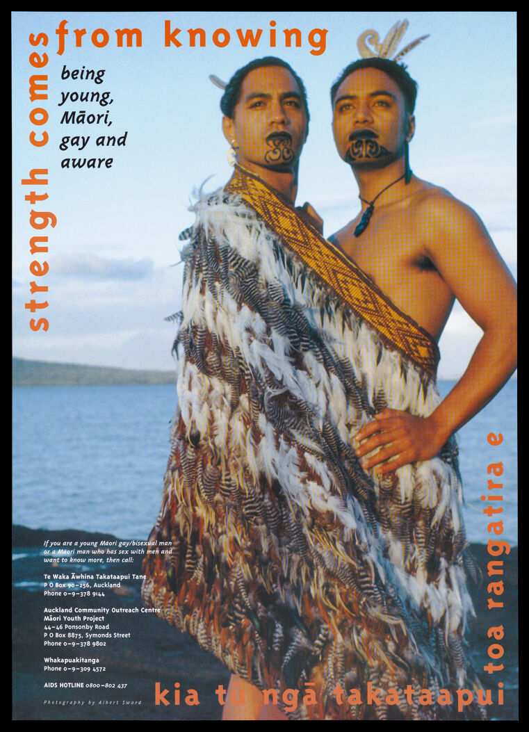 Two young Māori men standing with face decoration and a feather wrap